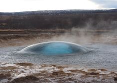 a large blue substance floating in the middle of a body of water with steam rising from it