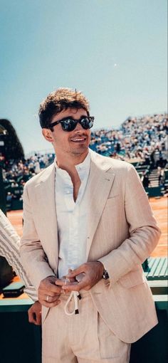 a man in a suit and sunglasses standing on a tennis court