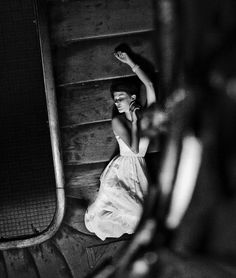 black and white photograph of woman in dress on stairs