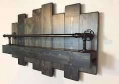 a wooden shelf with metal pipes mounted to it's sides and on the wall