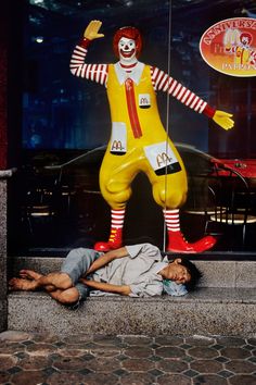 a man laying on the ground next to a statue of a ronald mcdonald's clown