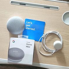 the google home mini is sitting next to an apple mouse and headphones on a table