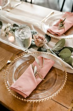 the table is set with pink napkins and place settings for an elegant dinner party