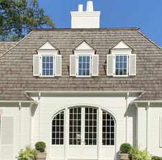 a white house with windows and shutters on the roof