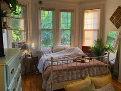 a bedroom with three windows and a bed in the corner next to two dressers