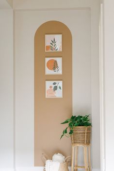 a room with some pictures on the wall and a plant in a basket next to it