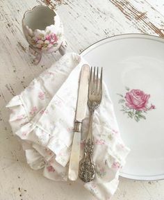 a white plate topped with a fork and knife next to a cup on top of a table