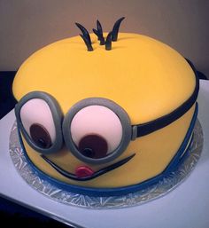 a yellow cake with googly eyes and glasses on top