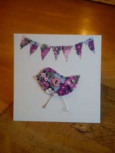 a card with a bird and bunting flags on the front, sitting on top of a wooden table