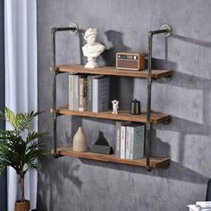 three wooden shelves with metal pipes and bookshelves against a gray wall in a living room