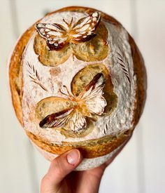 a person holding a loaf of bread with flowers on it