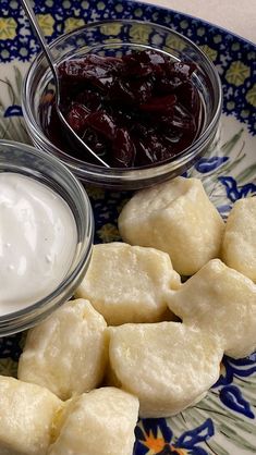 some food on a blue and white plate next to a bowl of cream cheese and cranberry sauce