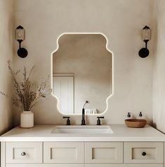 a bathroom sink with a large mirror above it and lights on the wall behind it