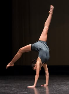 a woman doing a handstand on the floor in front of a black background