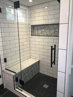 a walk in shower sitting next to a white tiled wall and black tile flooring