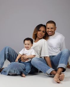 a man and woman sitting on the ground with a baby