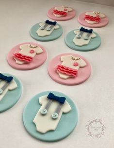 decorated cookies are arranged in the shape of baby's clothes on blue and pink plates