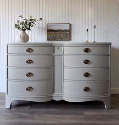 a white vase sitting on top of a gray dresser