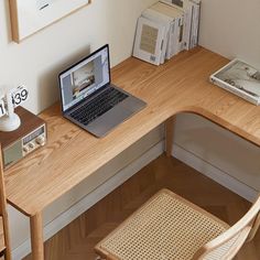 a laptop computer sitting on top of a wooden desk next to a stack of books