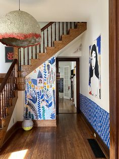 the hallway is decorated with colorful wallpaper and wooden stairs leading up to the second floor