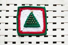 a crocheted christmas tree ornament hanging on a white woven piece of cloth