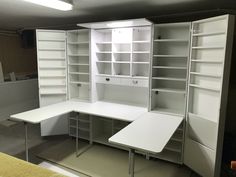 an empty white desk and shelves in a room