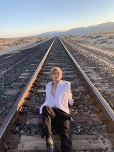 a man sitting on train tracks in the middle of nowhere