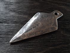 a piece of metal sitting on top of a wooden table next to a bottle opener