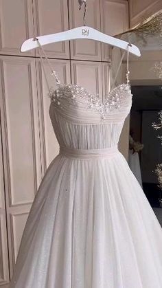 a white wedding dress hanging on a hanger