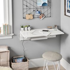 a white desk and chair in front of a window with pictures hanging on the wall