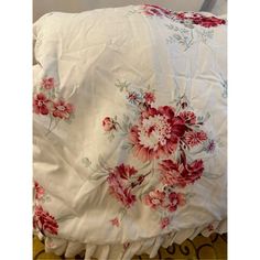 an unmade bed with red and white flowers on it