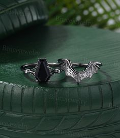 a ring with a bat design on it sitting on top of a green cushioned surface