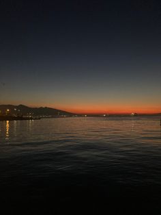 the sun is setting over the water and buildings are in the distance