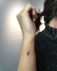 a woman's arm with a small spider tattoo on the left side of her wrist