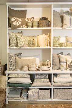 a white shelf filled with lots of pillows and other decorative items on top of it