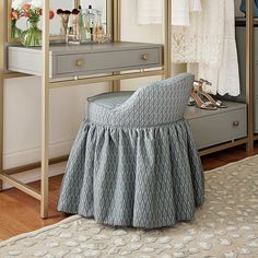 a dressing table with a mirror, stool and clothes hanging on the rack in front of it