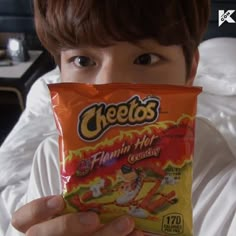 a person holding up a bag of cheetos in front of their face and looking at the camera