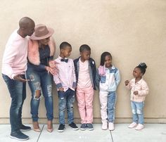 a group of children standing next to each other in front of a wall with their hands together