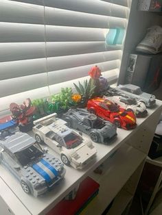 some toy cars are sitting on a white table in front of a window with blinds