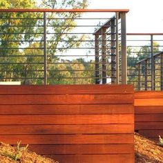 two wooden planters sitting next to each other on the side of a hill with trees in the background