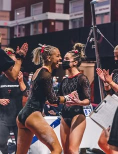 three female cheerleaders in black and white outfits with their hands together as they dance