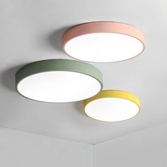 three circular lights hanging from the ceiling in a room with white walls and flooring