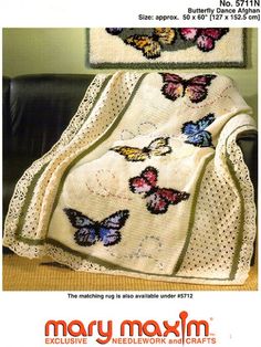 a white blanket sitting on top of a chair next to a black leather couch with butterflies on it