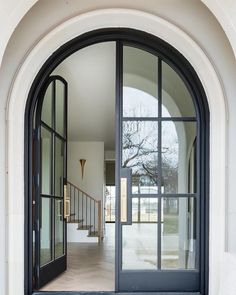 an open door leading into a large white building with black trim and glass doors on both sides