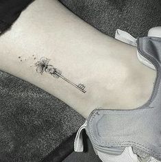 a small dandelion tattoo on the right side of the ankle is shown in black and white