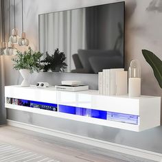 a white entertainment center with blue lights on the bottom shelf and a large mirror above it