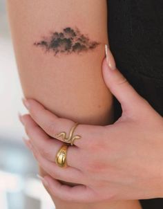 a woman's arm with a cloud tattoo on the left side of her body