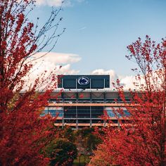 the building is surrounded by trees with red leaves on it and blue sky in the background