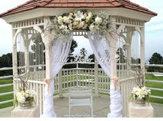 a white gazebo with flowers and greenery on it