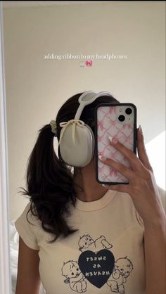 a woman wearing headphones is taking a selfie with her phone and ear phones